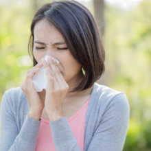 Woman with sneezing and runny nose caused by seasonal allergies