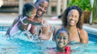 Family enjoying time together in a swimming pool while practicing swim safety.