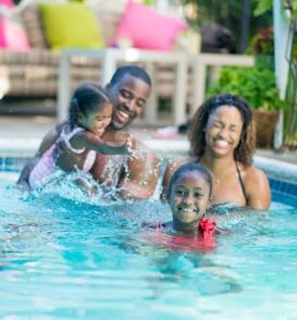 Family enjoying time together in a swimming pool while practicing swim safety.